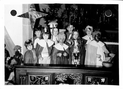Ein Foto von 1971. Neuen Sternsinger stehen in einer Kirche und tragen festliche Gewänder und halten den Stern in die Höhe.