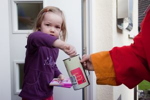 Ein kleines Mädchen spendet Geld und Schokolade an die Sternsinger.