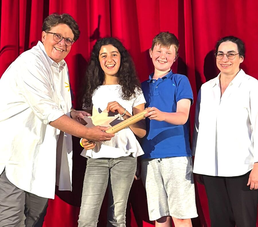 Nach zwei erfolgreichen Benefizkonzert-Abenden übergibt unsere Kollegin Daniela Dicker den Staffelstab an Narin und Jonathan, die Schulsprecherin und den Schulsprecher der Carl-Orff-Grundschule in Berlin. Rechts die stolze Schulleiterin Domenica Acri. // © Anette Aßmuth / Carl-Orff-Schule, Berlin