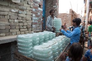 Pappu bei Beladen eines Karren mit fertigen Armreifen, Azad Nagar, Indien