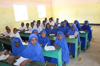 Auf dem Bild ist eine Schulklasse in Somalia zu sehen: Die Jungen tragen weiße Hemden, die Mädchen tragen blaue Hidschabs. 