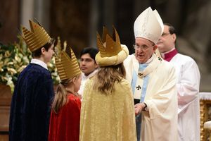 Drei Sternsinger stehen vor Papst Franziskus. Sie haben die traditionellen Gewänder an. Die Sternsinger haben an der Gabenprozession teilgenommen. Der Papst spricht zu den Sternsinger und bedankt sich für das Engagement der Kinder und Jugendlichen.