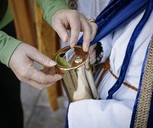 Ein Sternsinger hält die goldenen Spendenbox. Eine andere Person wirft einen Geldschein und die Spendenbox.