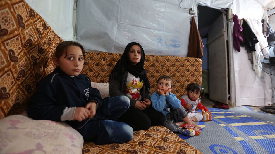 Khadija sitzt zusammen mit ihrer Mutter und den zwei kleineren Geschwistern auf dem Boden der mit Decken ausgelegt ist.