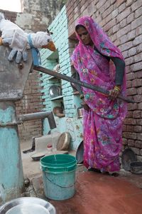 Es gibt auch keine Wasserhähne in den Hütten. Diese Frau erzählt mir, dass sie das Wasser mit einem Hebel nach oben pumpen muss. Dann muss sie es nach Hause schleppen, um damit zu waschen, kochen und zu spülen. Fast immer ist es Aufgabe der Frauen und Mädchen, Wasser zu holen.