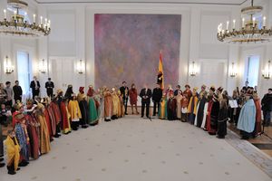 Bundespräsident Joachim Gauck und seine Frau Daniela zusammen mit den Sternsingern im Innern des Schloss Bellevue. Auf der rechten Seite stehe Sternsinger mit Instrumenten wie z.B. einer Oboe. Die Sternsinger auf der linken Seite haben keine Instrumente dabei. Die Sternsinger sind festlich gekleidet. Sie tragen bunte Umhänge und goldene Kronen. Einige haben den Sternsinger Stern an einem langen Stock dabei und halten den Stern in die Höhe. Bundespräsident Joachim Gauck spricht zu den Sternsingern.