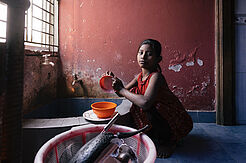 Ein junges Mädchen spült und ist betroffen von Kinderarbeit in Bangladesch