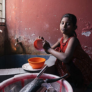 Ein junges Mädchen spült und ist betroffen von Kinderarbeit in Bangladesch