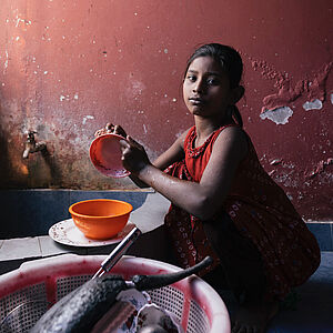 Ein junges Mädchen spült und ist betroffen von Kinderarbeit in Bangladesch