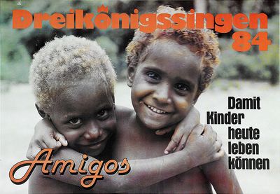 Ein Plakat zu Bewerbung der Aktion Dreikönigssingen 1984. Abgebildet sind zwei Kinder die sin gegenseitig in den Armen halten und freudig lachen. Beide Kinder haben kurze stark gelockte Haare und tragen keine Kleidung am Oberkörper. Unten links in der Ecke des Plakates steht das Wort "Amigos" Das bedeutet Freunde. In der rechten Ecke steht der Slogan "Damit Kinder heute leben können." Am Kopfende des Plakats steht in orange farbebner Schrift Dreikönigssingen´84.