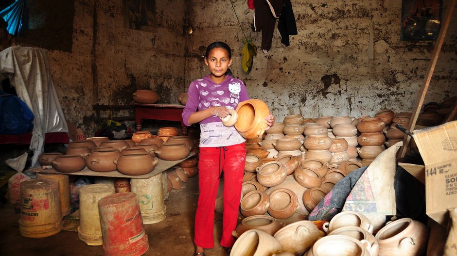 Das Mädchen Meche in der Keramikwerkstatt ihrer Eltern. Sie hält einen der vielen Töpfe in der Hand
