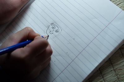 Konzentriert sitzt Nour auf dem Zeltboden und zeichnet mit dem Bleistift ein Gesicht auf ein Blatt Papier. 