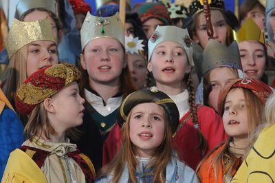 Eine große Gruppe der Sternsinger singt ein Lied. Alle haben die Gewänder und Kronen an. Manche Kronen sind reich geschmückt. 