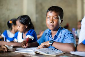 7_Tag gegen ausbeuterische Kinderarbeit Sohag sitzt in einem Klassenzimmer von ARKTF und lernt. Er hat vorher in einem Hotel gearbeitet. Jetzt verkauft er mittags nur noch manchmal das Essen welches seine Mutter gekocht hat.Er hat ein blaues Hemd an.