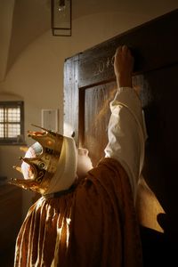 Ein Sternsinger mit Krone und gekleidet in ein Gewand, schreibt den traditionellen Segen der Sternsinger an eine Haustür. Der Sternsinger muss sich Strecken um bis ganz nach oben zu kommen. 