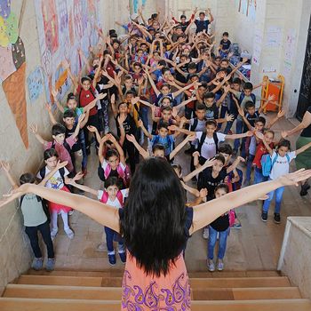 Schülerinnen und Schüler der Schule in Latakia strecken die Arme in die Luft. 