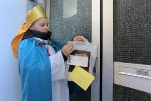 Leni (8) nimmt einen Beutel mit Sueﬂigkeiten und Geldumschlag von einer Haustuere in Osnabrueck. 