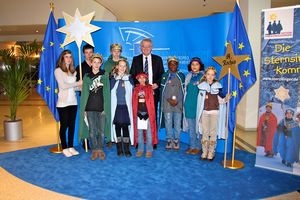 Die Sternsinger zu Gast im EU- Parlament. Vizepräsident des EU- Parlaments, Rainer Wieland, empfängt und begrüßt sie. Die Sternsinger aus der Pfarrei St. Rochus aus dem Seelsorgebereich Kerpen Süd- West haben bunte Umhänge und goldene Kronen an. Rainer Wieland steht in der Mitte des Sternsingergruppe.