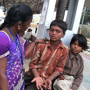 Eine Streetworkerin spricht mit Straßenkindern und kümmert sich um sie.