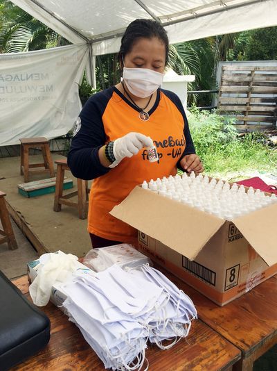 ALIT-Geschäftsführerin und Sternsinger-Partnerin Yuliati Umrah packt Kisten mit Desinfektionsmittel und Masken. 