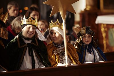 Sternsinger beim Gottesdienst. Sie haben Kronen und Umhänge sowie den Stern dabei. Sie sitzen in der ersten Reihe der Kirche.