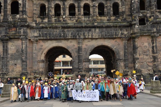 Treffpunkt Porta Nigra: 2.659 Sternsinger feiern am Freitag, 29. Dezember, in Trier die bundesweite Eröffnung ihrer 60. Aktion Dreikönigssingen. Hier laufen die Sternsinger grade durch das Porta Nigra in Trier und tragen das Banner mit dem Slogan der Sternsinger voran. Der Slogan lautet Segen bringen, Segen sein.