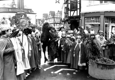 Ein Foto von 1988. Eine große Gruppe Sternsinger sind in einer Fußgängerzone und singen. In ihrer Mitte steht sogar ein echtes Kamel