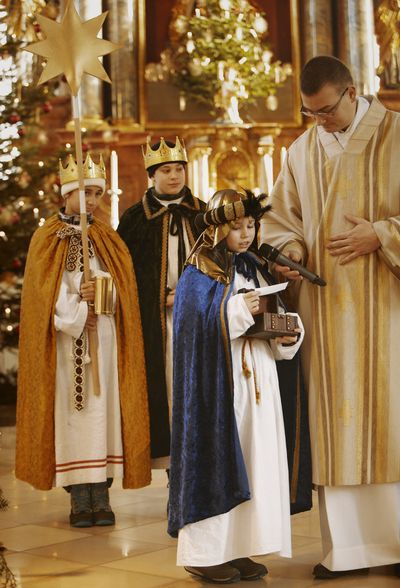 Drei Sternsinger sind Teil des Gottesdienstes. Ein Sternsinger bekommt das Mikrofon durch den Priester herangereicht und spricht.