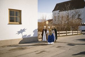 Vier Sternsinger auf dem Weg von der Kirche zu den Menschen nach Hause. Sie sind in die traditionellen Gewänder gehüllt, tragen Kronen und den Stern von Betlehem.