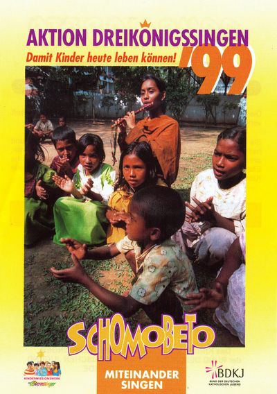 Ein Aktionsplakat zur Aktion Dreikönigssingen 1999. Das Aktionsland ist Bangladesch. Abgebildet sind sieben Kinder und eine Lehrerin. Die Mädchen und Jungen singen und klatschen während die Lehrerin begleitend auf einer traditionellen Flöte aus Bangladesch spielt. Die gesamte Szene spielt sich draußen im Grünen ab. Alle hocken zusammen auf dem Boden. In derKopfzeile steht Aktion Dreikönigssingen ´99. Direkt darunter der Spruch: Damit Kinder heute leben können. In der Fußzeile steht Schombeto, das Wort bedeutet miteinander Singen.  