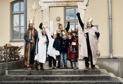 Sechs Sternsinger stehen auf eine Treppe, reißen die Arme noch oben und lachen!