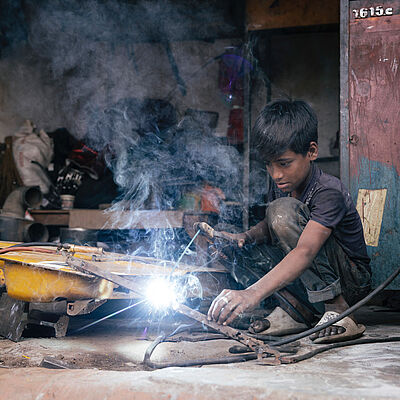 Ein Junge beim Schweißen ohne Schutzkleidung ist betroffen von Kinderarbeit in Bangladesch