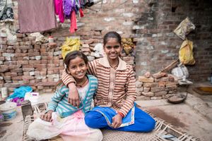 Reportage_Neetu_Aktuell Besuch bei Neetu (braun-weiß gestreifte Jacke) und Jyoti (blau-weiß gestreifte Jacke), die in der indischen Stadt Firozabad Armreifen zusammenschmelzen. Dank der Hilfe der Sternsinger können die beiden nun auch zur Schule gehen. Die Vikas-Stiftung hat außerdem ein Kinderparlament in ihrem Stadtteil in Firozabad ins Leben gerufen, das die beiden Mädchen besuchen.