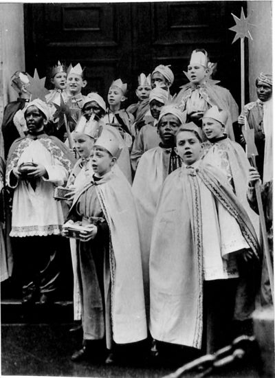 Ein Foto von 1960. #Auf dem Foto ist eine große Gruppe Sternsinger. Die Sternsinger haben lange Gewänder an, tragen Kronen und singen.