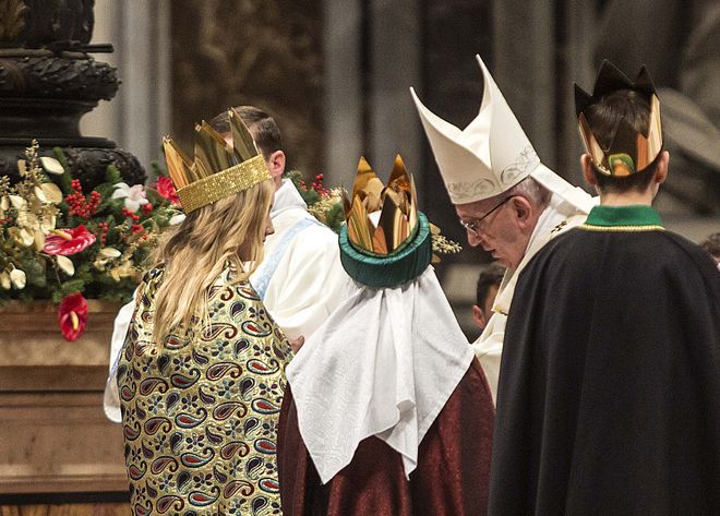 Drei Sternsinger stehen vor Papst Franziskus. Sie haben die traditionellen Gewänder an. Die Sternsinger haben an der Gabenprozession teilgenommen. Die drei stehen direkt vor dem Papst.