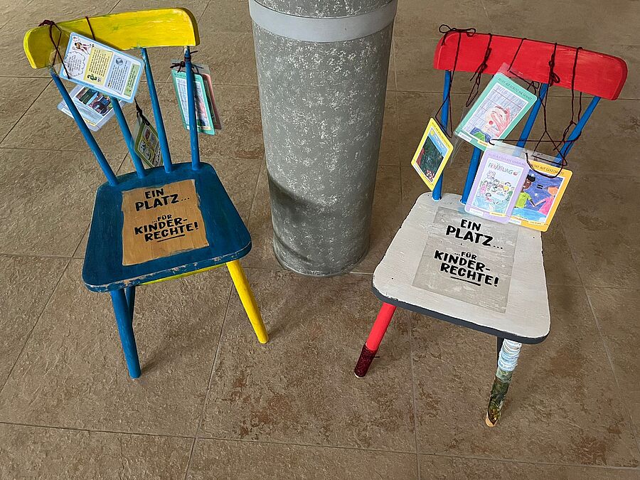 Unsere Stühle stehen in unserer Herz-Jesu Kirche auf dem Weg zum Ausgang, wo ein jeder vorbeikommt. Wir haben die schönen Kinderrechtekarten mit langen Bändeln versehen, damit sie bequem gelesen werden können und so zum Nachdenken anregen und nicht nur Schlagworte bleiben. // © Iris Freiwald