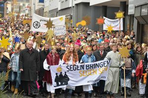 Sternsingerzug mit 2.500 Sternsingern zieht durch die Paderborner Innenstadt. Die Straße auf der normalerweise die Autos fahren ist voller Menschen in Gewändern und Kronen.